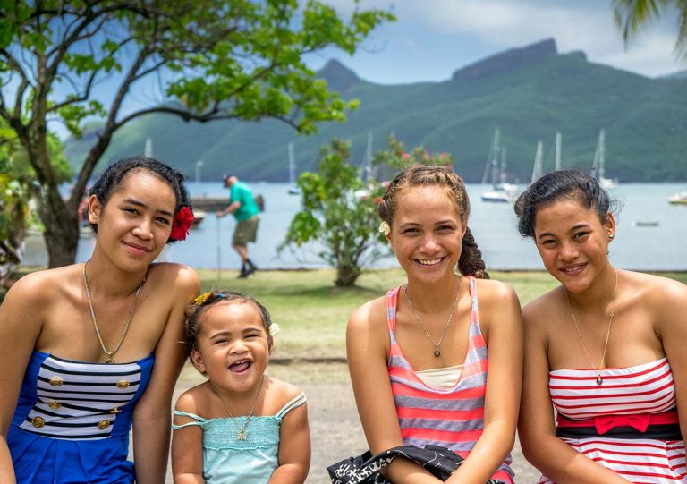 smiling girls sitting on bench in tropical country