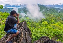 Khao Sok: A Tropical Jungle Nature Experience in Thailand Man taking photograph of Khao Sok National Park, Thailand, from high viewpoint