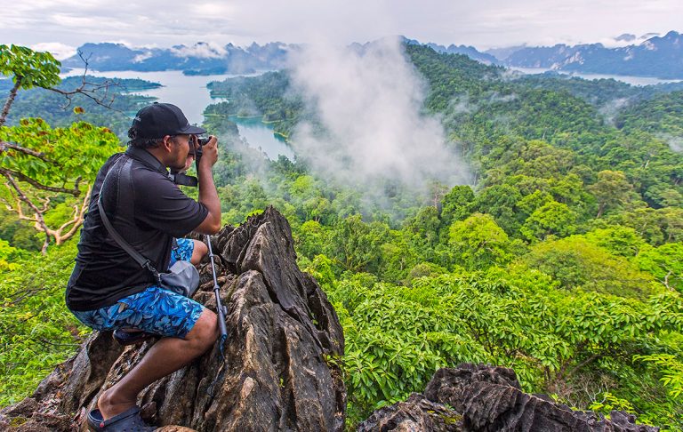 Man taking photograph of Khao Sok National Park, Thailand, from high viewpoint