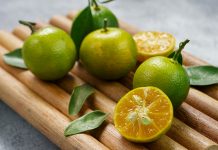 The Calamansi: Southeast Asia’s Dwarf Lime Five ripe calamansi fruit on a bamboo tray with one cut open to show the juicy inside.