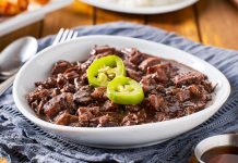 How To Prepare Dinuguan, the Filipino Blood Stew A white bowl on a table containing Filipino pork blood stew known as dinuguan garnished with two slices of green chili pepper.